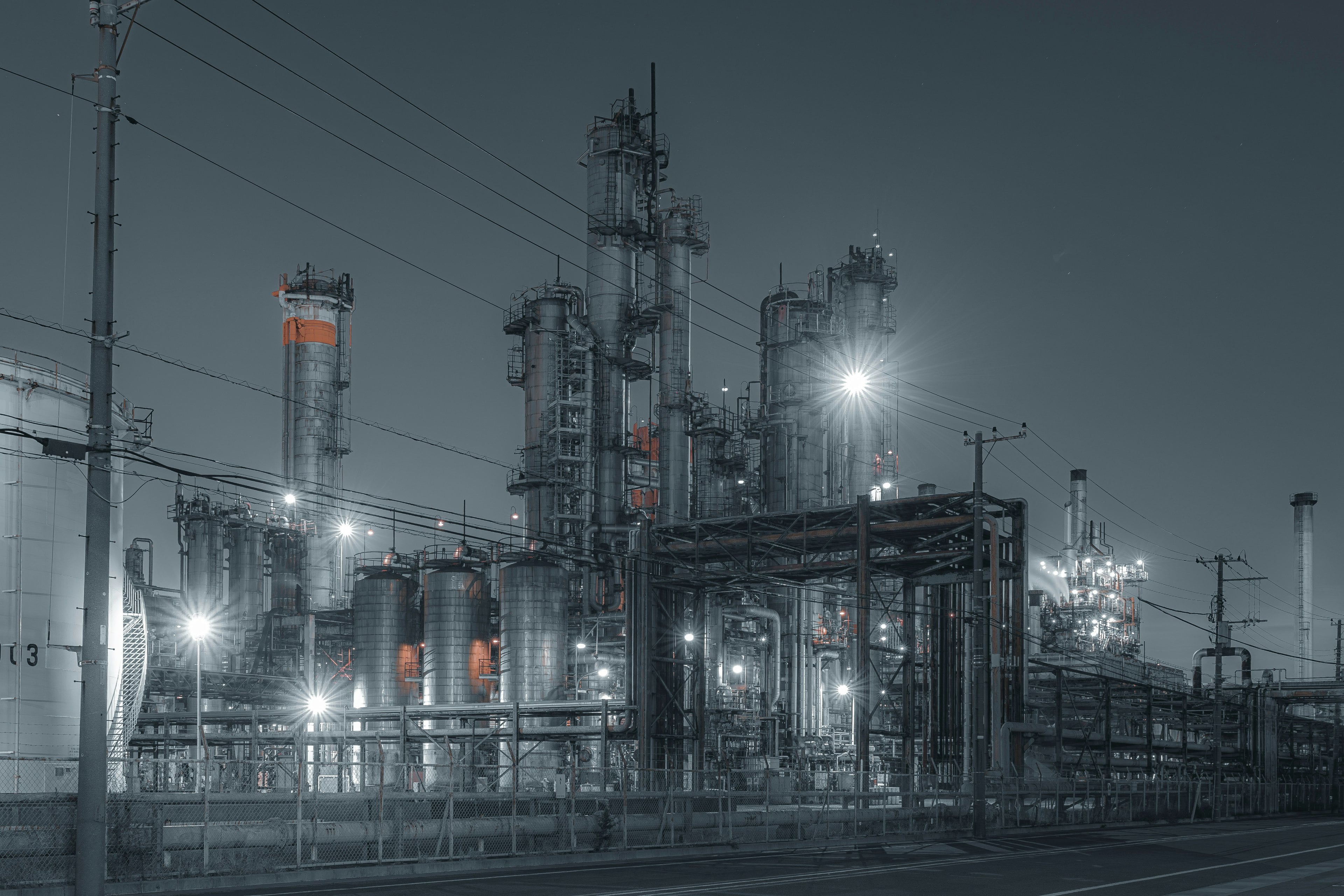 Usine pétrochimique de nuit, éclairée par des projecteurs : colonnes de distillation, réacteurs et capacités en acier inoxydable