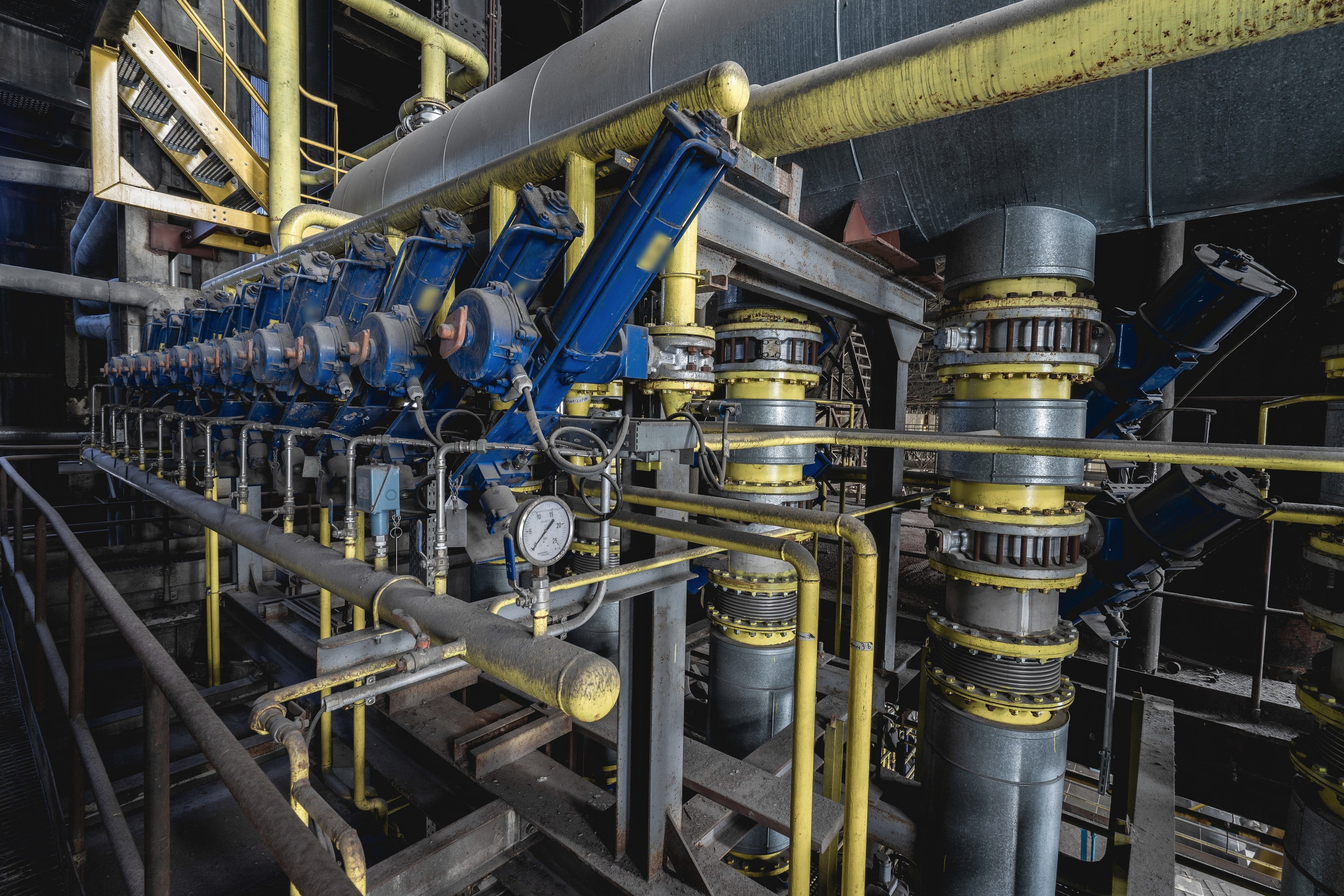 Actionneurs de vannes bleus sur des tuyauteries procédé jaunes, avec compensateurs de dilatation à soufflet, sous une gaine calorifugée au niveau de la chaudière d’une centrale électrique