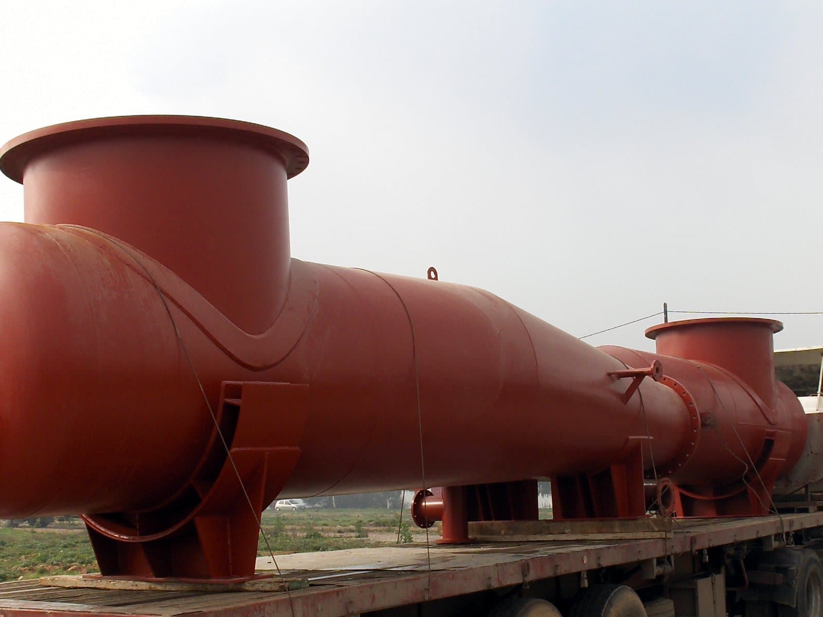 A long primed steel header with two large branches loaded on a road trailer