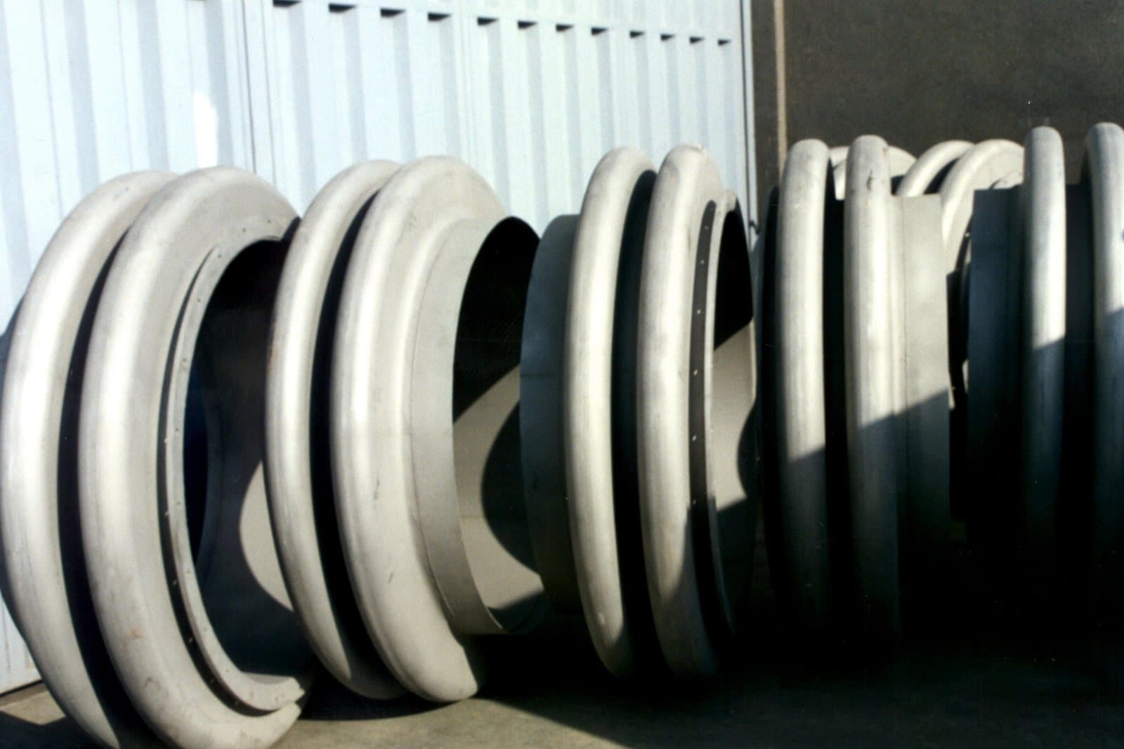 Large-diameter stainless steel expansion bellows stored against the workshop wall